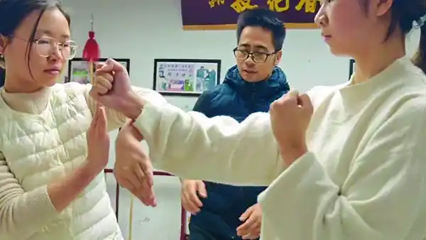 Master Liu teaching Wing Chun techniques to two young women in a training session.